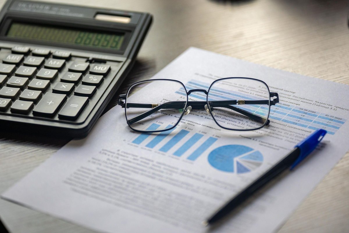 Calculator, pen and glasses resting on a printed financial report