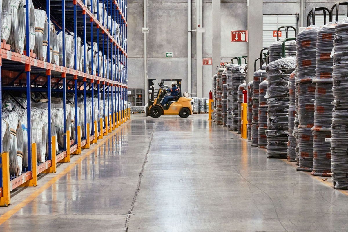Forklift moving between pallet racking aisles in a logistics warehouse