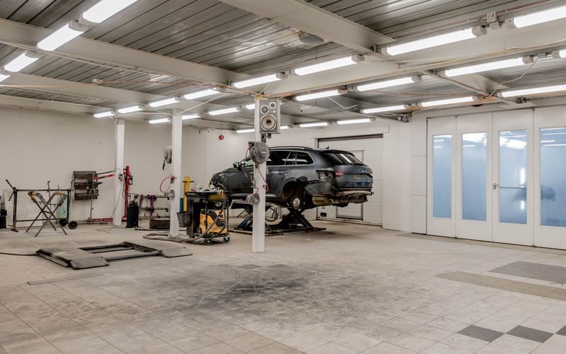 Vehicle raised on a two-post lift inside a professional automotive workshop